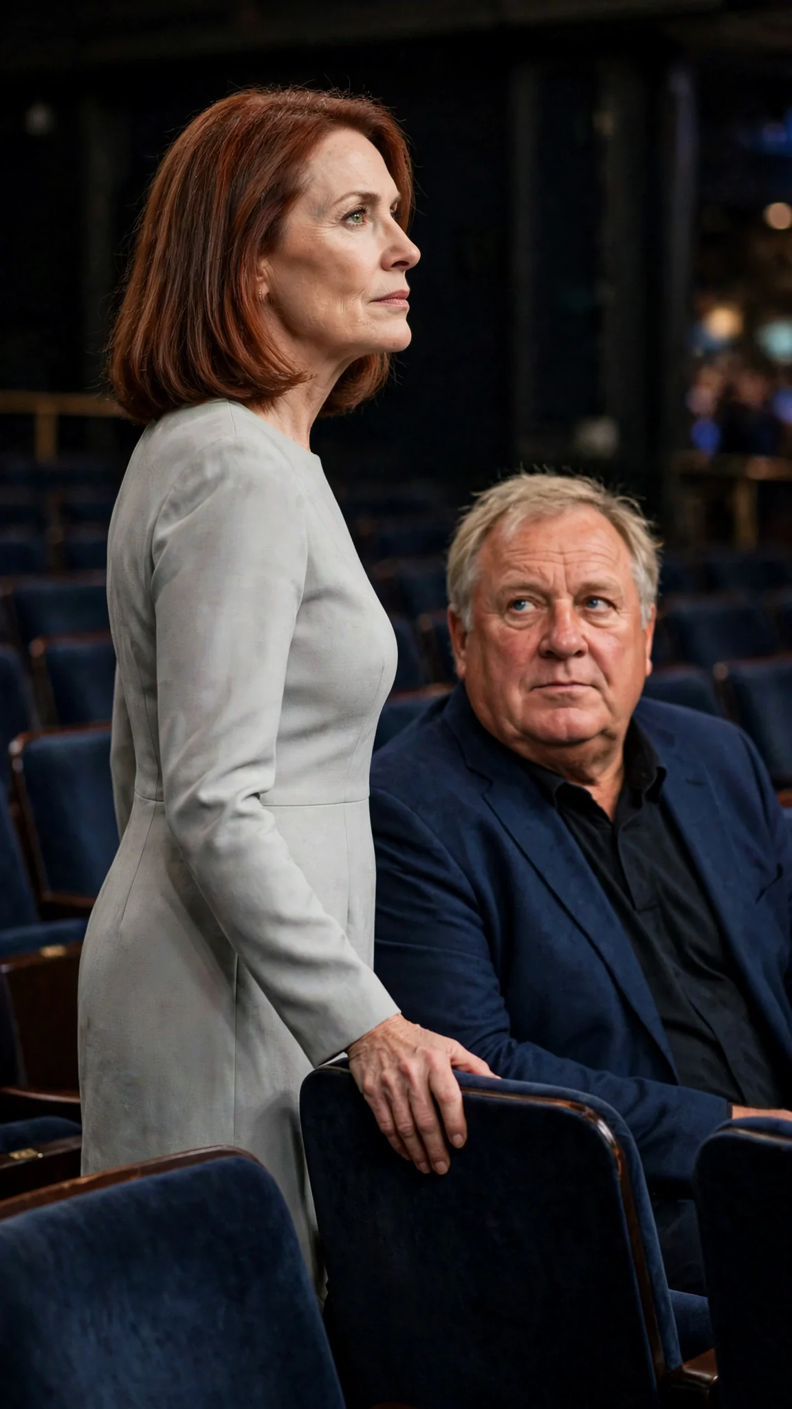 Lavinia turns in her chair to face Marielle on the stage, her chin high.