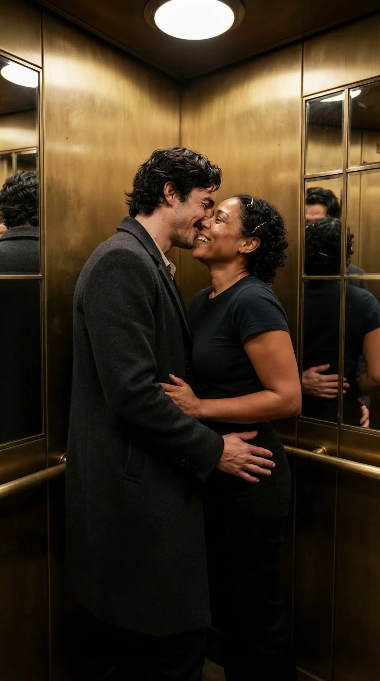 A man and a woman kiss in a small hotel elevator, both laughing, hands in each other's coats.