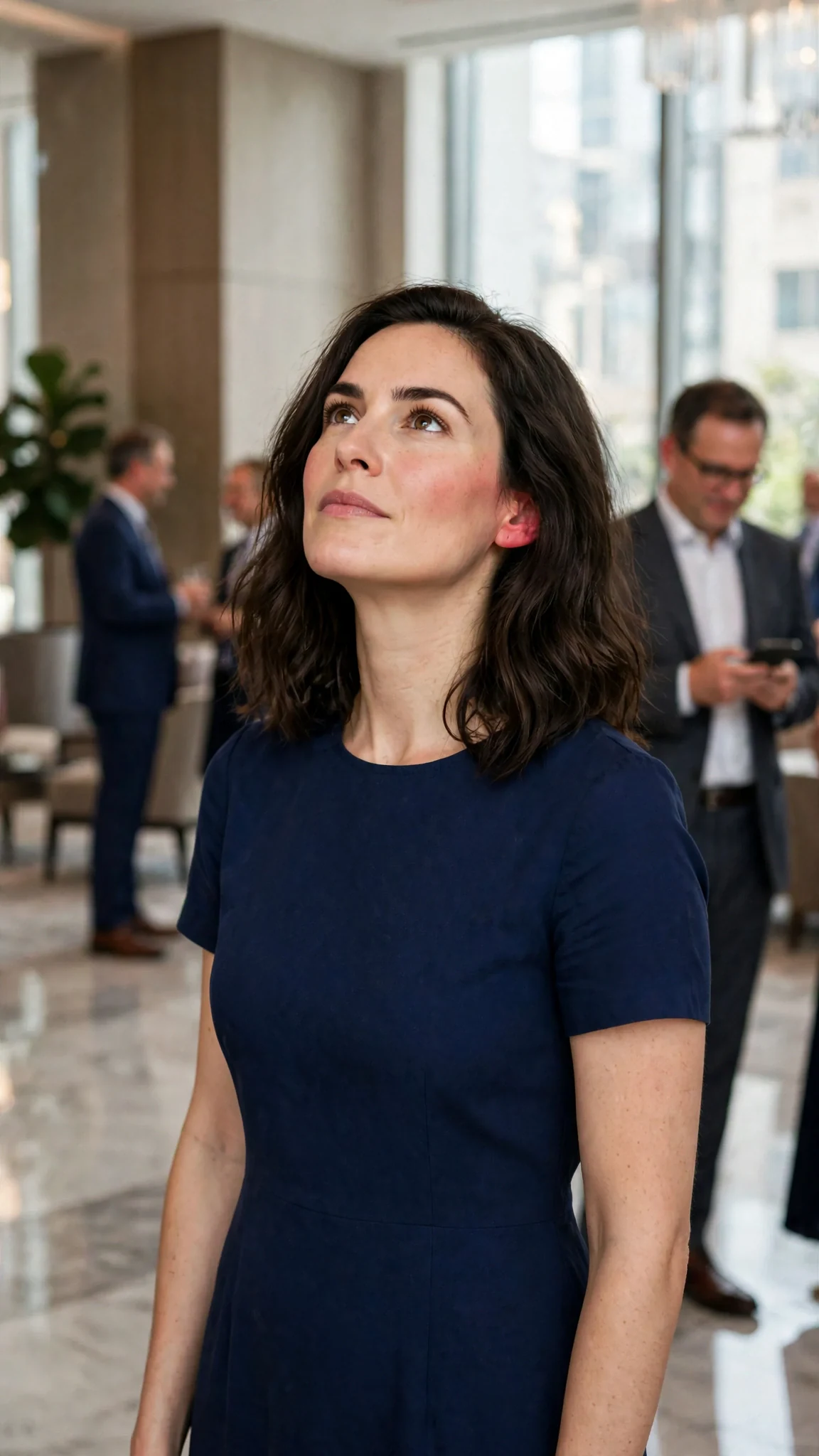Lena in the lobby, chin up, while a man nearby smirks at his phone.