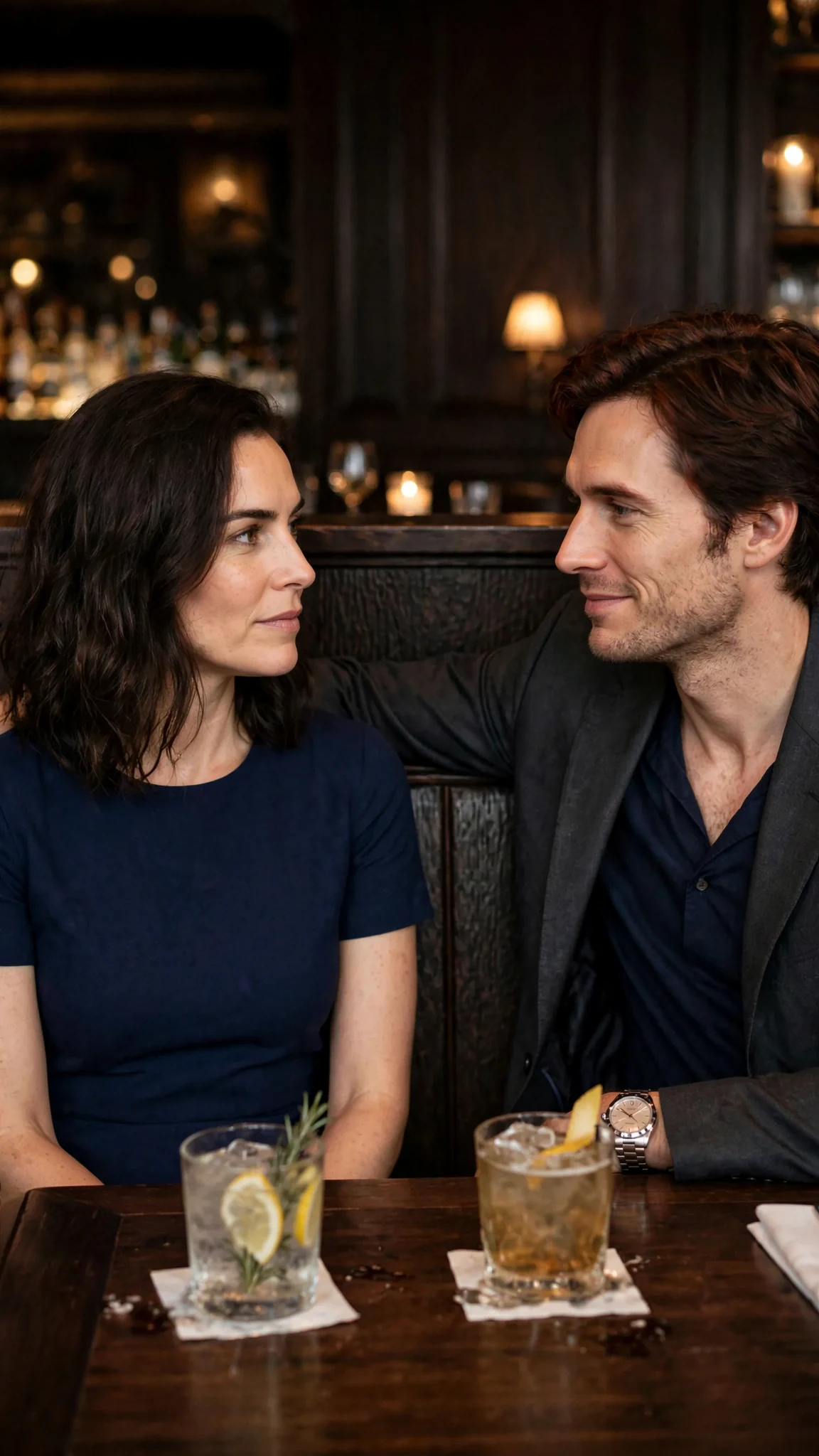 Lena and Kellan settle into a back booth with drinks.